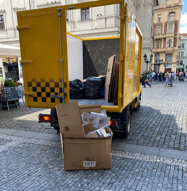 Otevřený vůz Odpad Taxi s krabicemi na dlažbě v centru Prahy